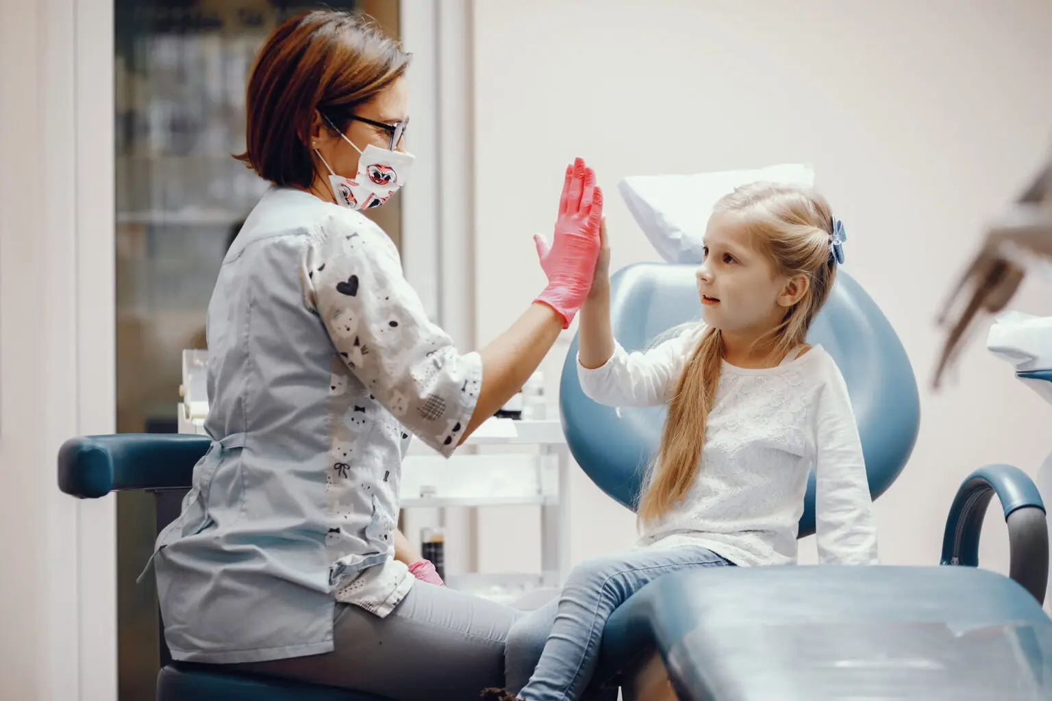 At Lake Sammamish Kids Dentistry - Pediatric Dentist in Sammamish WA, a friendly dental professional wearing gloves and a mask gives a high-five to a young patient—one of the many reasons 2,847 families trust us for exceptional care.