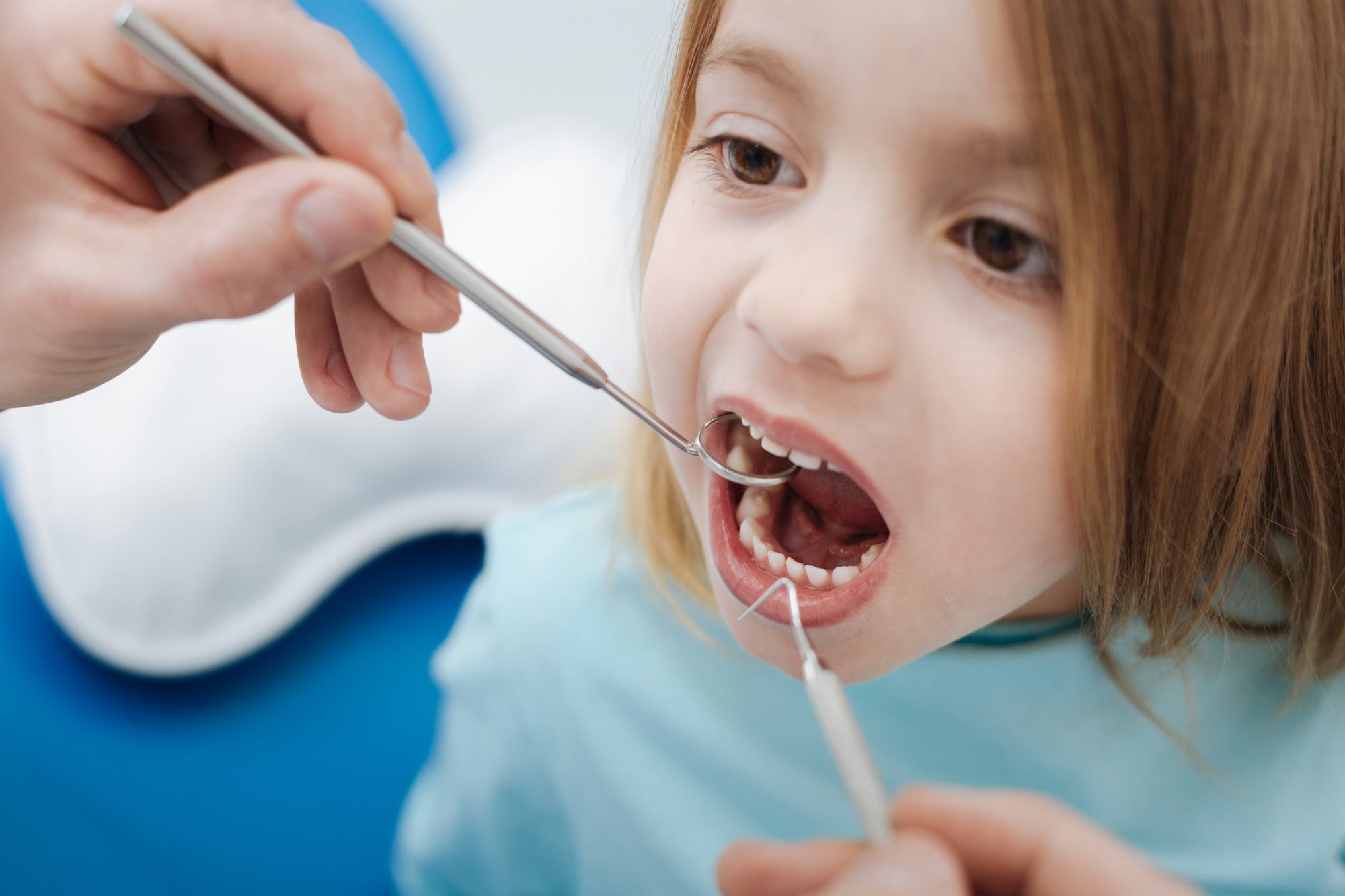 At Lake Sammamish Kids Dentistry - Pediatric Dentist in Sammamish WA, a dentist uses specialized instruments to examine a child's mouth, emphasizing the value of restorative dentistry for children, such as same-day digital crowns.