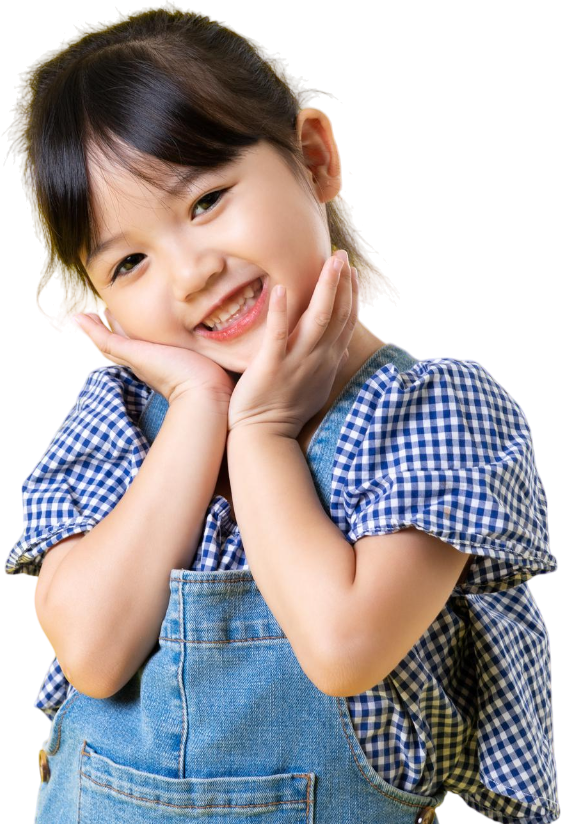 A young girl with dark hair, dressed in a blue checkered shirt and denim overalls, smiles sweetly with her cheeks resting in her hands against a white background. Lake Sammamish Kids Dentistry - Pediatric Dentist captures joyful moments like this for children in Sammamish, WA.