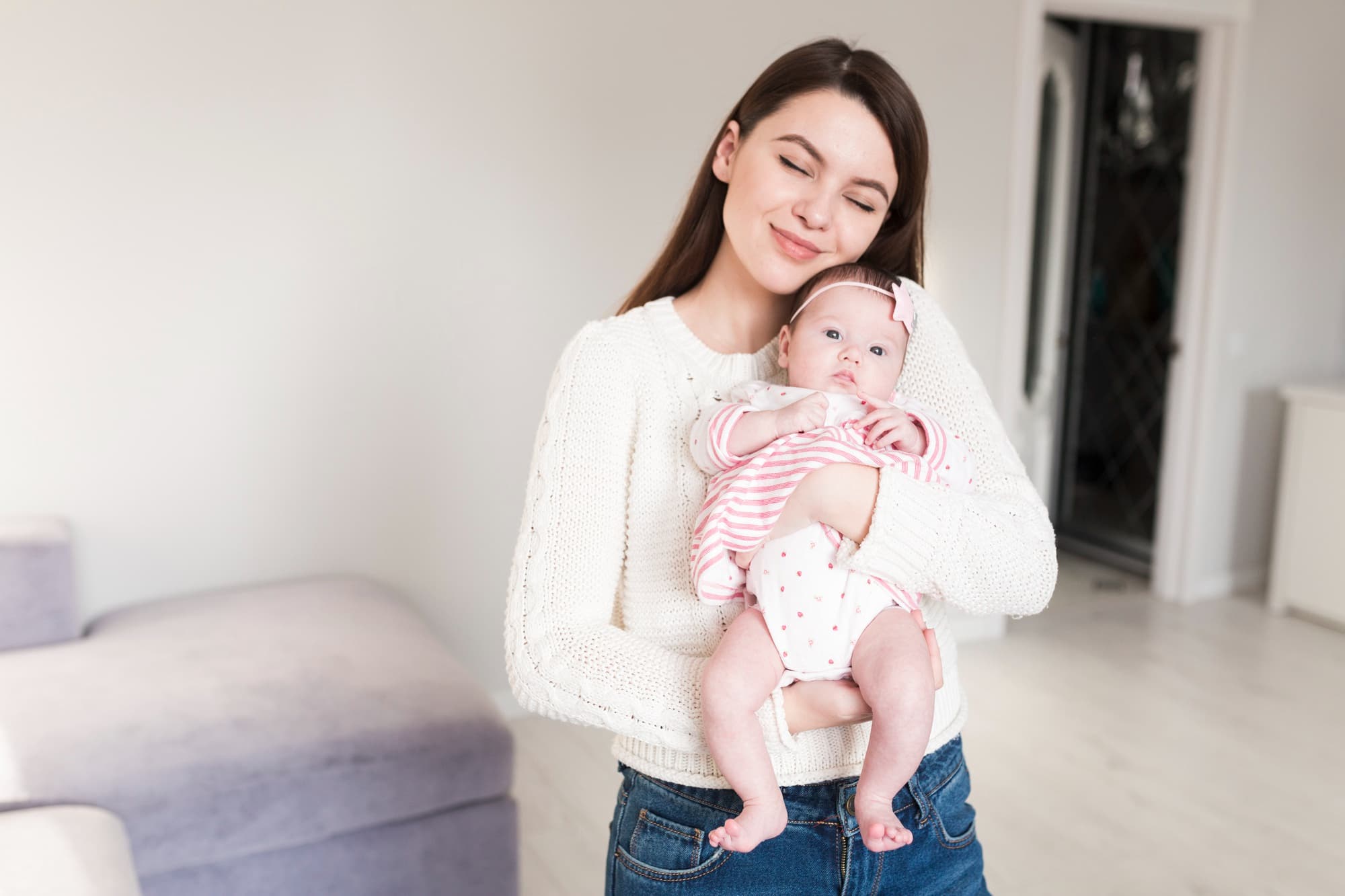 At Lake Sammamish Kids Dentistry - Pediatric Dentist in Sammamish WA, a woman in a white sweater holds a baby in pink and white stripes with a bow headband, emphasizing the importance of baby dentist visits for Apple Health ABCD Program—offering $0 dental care for ages 0–6.