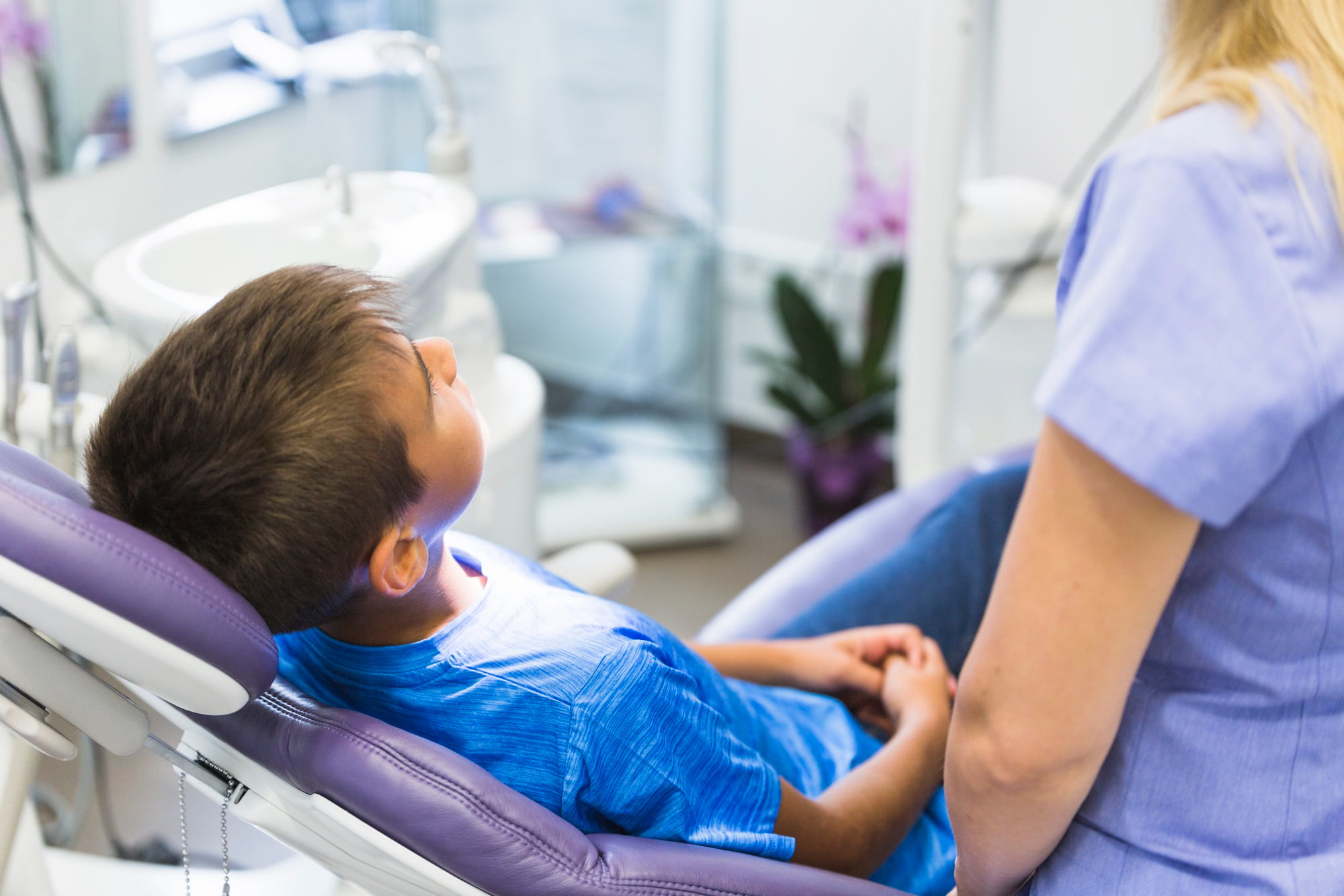 At Lake Sammamish Kids Dentistry - Pediatric Dentist in Sammamish WA, a young boy in a blue shirt sits comfortably in a dental chair while receiving IV sedation for complex procedures from an experienced dental professional.
