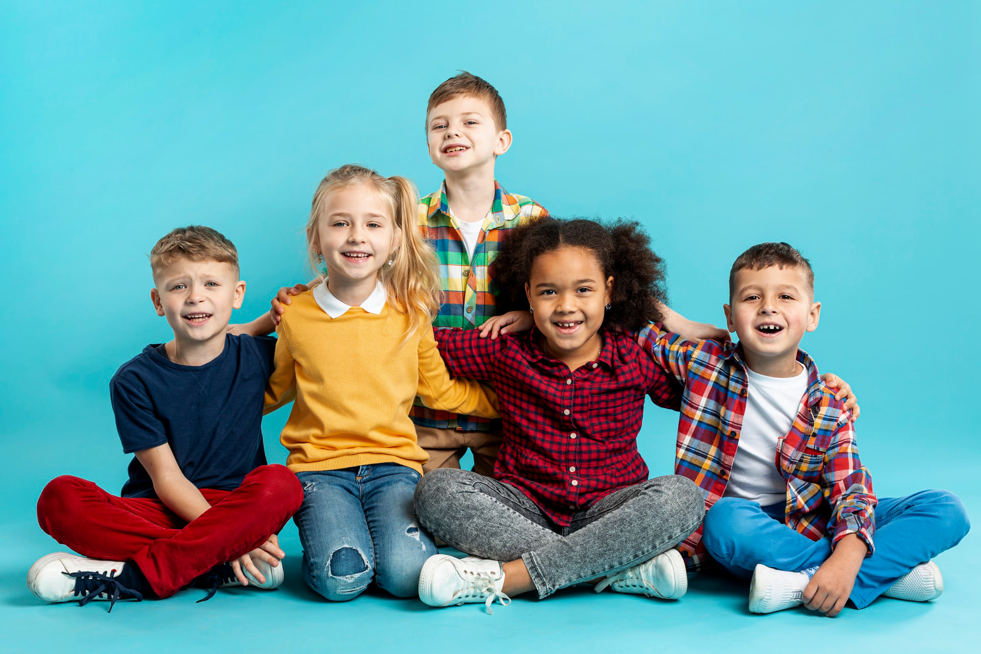 Smiling in front of a blue background, five casually dressed friends show how kids can rely on Lake Sammamish Kids Dentistry - Pediatric Dentist in Sammamish, WA for emergency pediatric dental care during business hours.