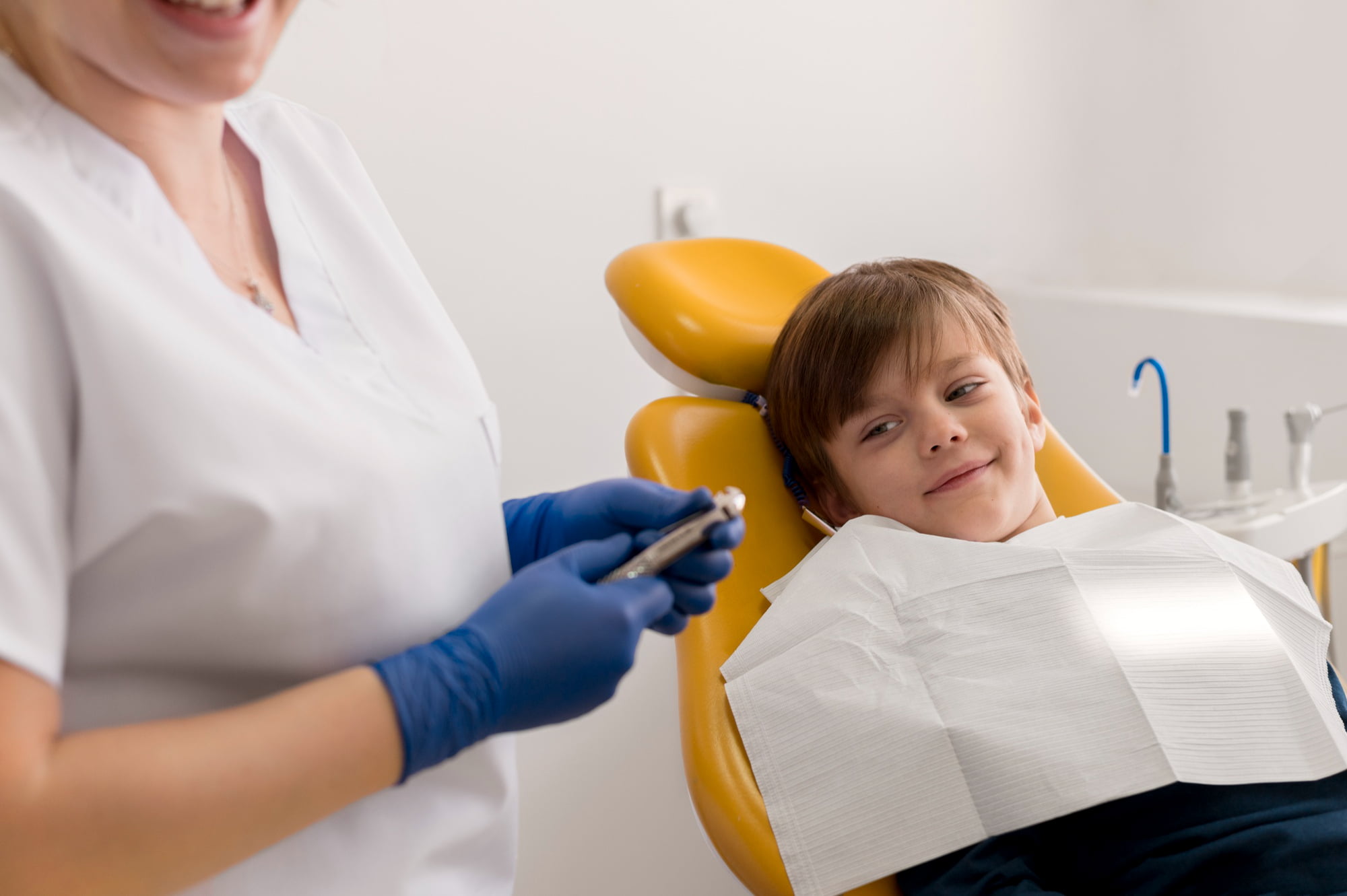 At Lake Sammamish Kids Dentistry - Pediatric Dentist in Sammamish WA, a young boy beams from a yellow dental chair, ready to say "Bye-Bye Drill, Hello Light" as the dental professional prepares for his brightest smile yet.