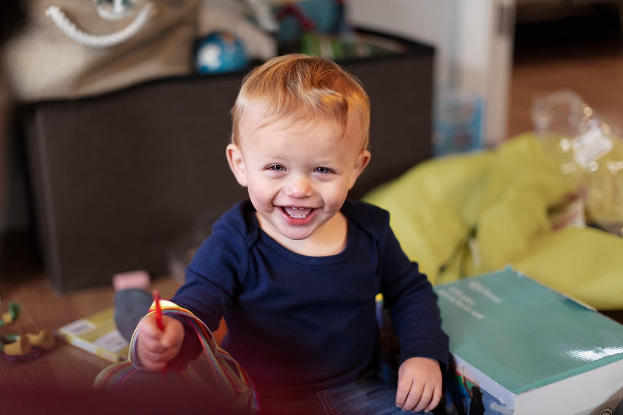Smiling after a recent tongue and lip-tie release in Sammamish, WA, this young child with light hair and a navy blue shirt enjoys colorful toys at Lake Sammamish Kids Dentistry - Pediatric Dentist.