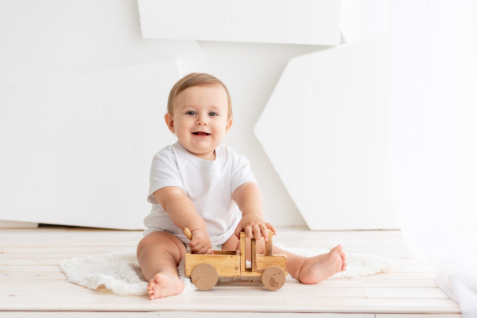 At Lake Sammamish Kids Dentistry - Pediatric Dentist in Sammamish WA, we know that early playtime—like a baby in a white onesie playing with a wooden toy truck—offers a great opportunity to teach parents about preventing baby-bottle tooth decay.