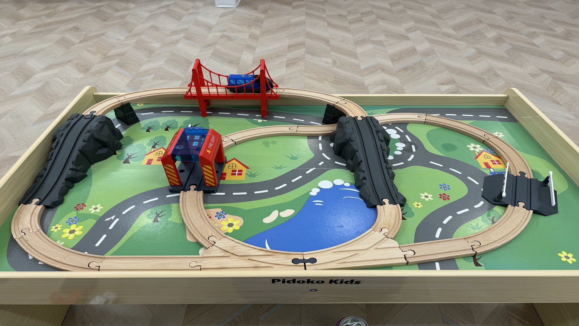 At Lake Sammamish Kids Dentistry - Pediatric Dentist in Sammamish, WA, a wooden toy train set with a red bridge, buildings, and figure-eight tracks sits atop a colorful play mat.
