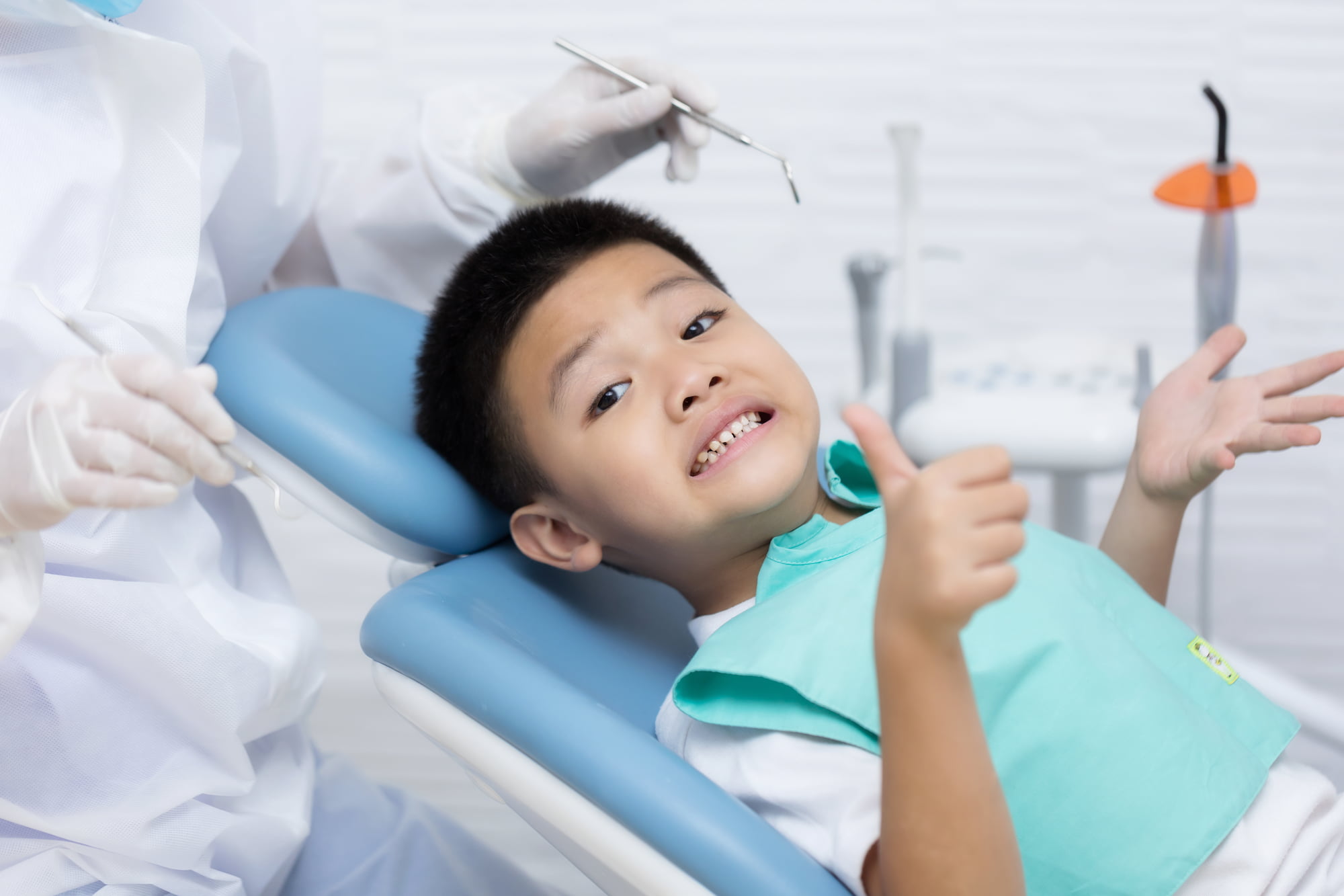 A young boy smiles and gives a thumbs up from the dental chair as a gloved dentist prepares tools—because at Lake Sammamish Kids Dentistry - Pediatric Dentist in Sammamish WA, having an emergency pediatric dentist ensures every second counts for knocked-out permanent teeth.