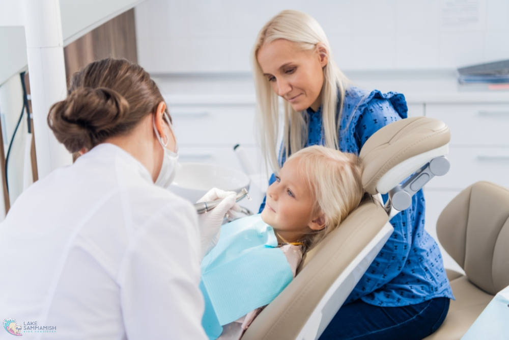 At Lake Sammamish Kids Dentistry in Sammamish, WA, a dentist checks a young child's teeth as a woman sits nearby in the clinic - Jaw Alignment Issues in Kids: Signs to Watch for in Sammamish, WA