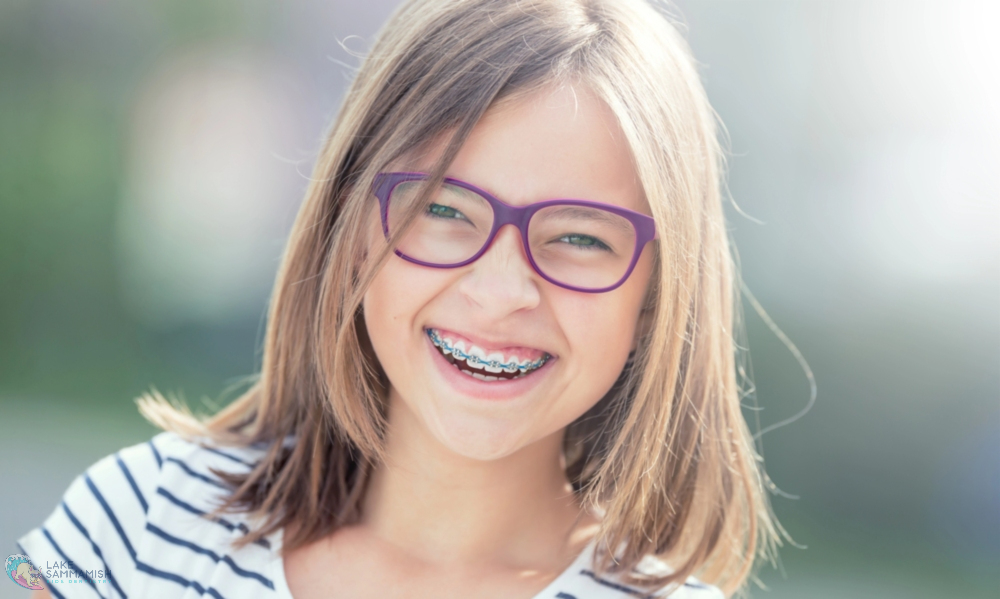 Smiling girl with shoulder-length hair, glasses, and braces outdoors in Sammamish, WA, for Lake Sammamish Kids Dentistry - Tooth-Friendly Snacks for Kids: Dentist Recommendations from Sammamish, WA 